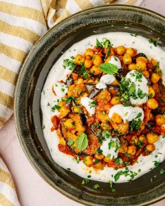 Melanzane e ceci speziati con salsa allo yogurt vegetale serviti in ciotola